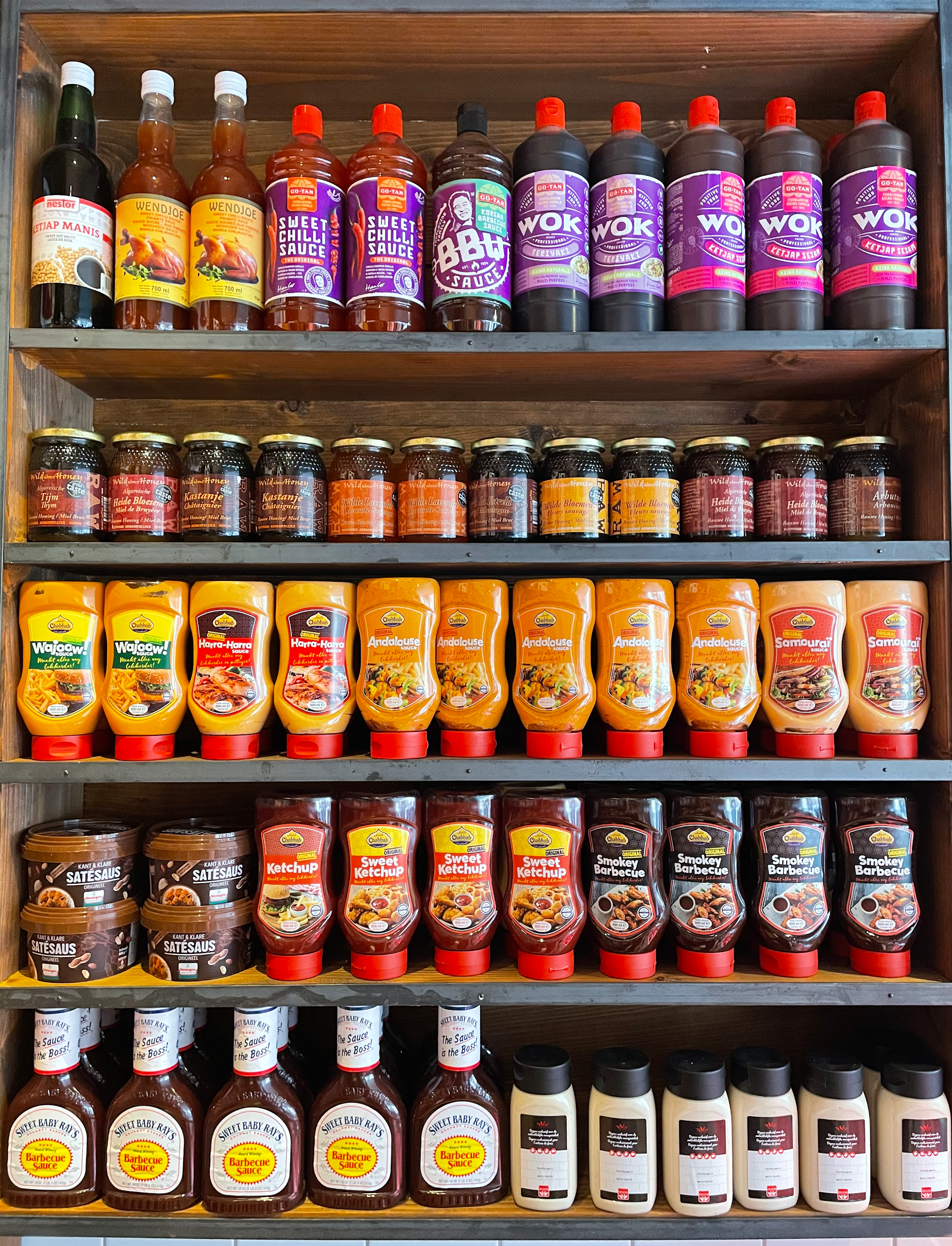 De wand met sauzen, honing en marinades in de winkel